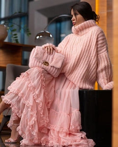 Detail of pink knit turtleneck sweater paired with ruffled tiered skirt and fuzzy bag