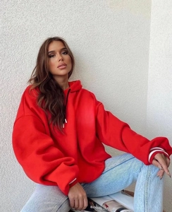 Detail view of red oversized hoodie featuring striped ribbed cuffs and black drawstrings