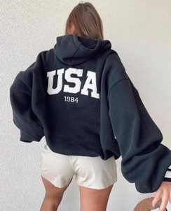 Detail view of oversized black hoodie featuring bold white USA 1984 graphic on the back