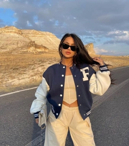 Detail view of a navy blue varsity jacket featuring a white embroidered letter F patch