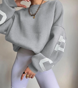 Detail of grey oversized sweatshirt with letter print on sleeves and ribbed leggings