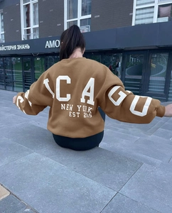 Close-up of brown oversized sweatshirt featuring retro Chicago white letter print