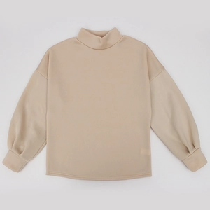 Detail of apricot turtleneck sweatshirt with ribbed cuffs and dropped shoulder seams