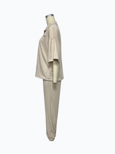 Close-up of beige knit two-piece set featuring short sleeve shirt with Studios Co. print