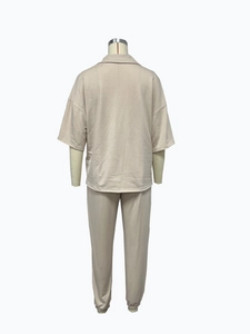 Detail view of the beige knit two-piece lounge set showing shirt collar and jogger cuffs
