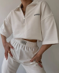 Detailed view of the half-zip collar and MAI STUDIOS embroidery on the off-white tracksuit