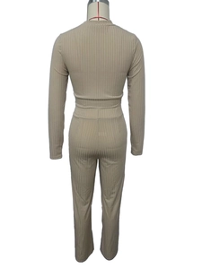 Macro view of light brown ribbed knit fabric and high-waist stitching on the jumpsuit