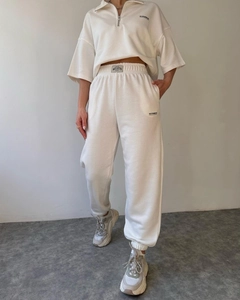 Detail of white two-piece sweatsuit showing MAI STUDIO CO text and high-waist joggers