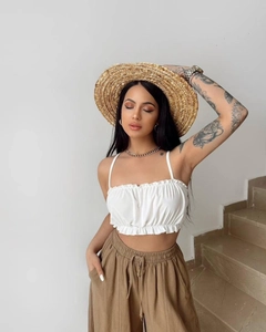 Detail of white ruffled cropped camisole top with drawstring and high waist wide leg pants