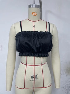 Detailed view of the black satin camisole featuring delicate ruffled edges and thin straps