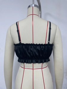Detail of black satin camisole back with elastic smocking and ruffle hem on a mannequin