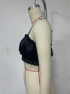 Detail of black satin camisole featuring delicate ruffled edges and slim shoulder straps