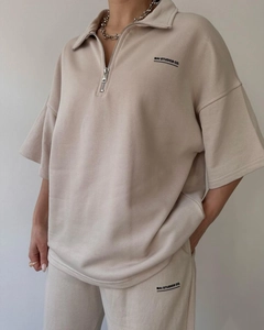 Close-up of the metal half-zipper and brand logo on this beige lounge two-piece set