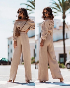 Detail of off-the-shoulder crop top and high-waisted wide-leg trousers in beige fabric