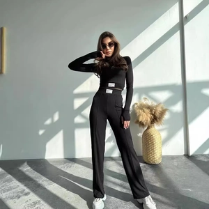 Women's black ribbed knit two-piece set featuring long sleeve crop top and flared trousers