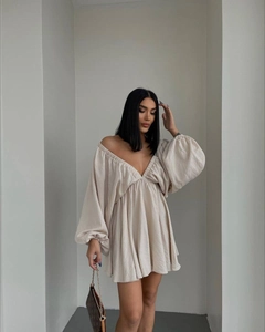 Detail eines beigen Off-Shoulder-Minikleides mit großen Laternenärmeln und V-Ausschnitt