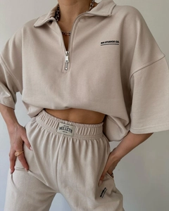 Detail view of beige two-piece lounge set with half-zip top and branded graphic print