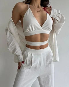 Gros plan sur l'ensemble trois pièces en lin blanc avec haut licou et pantalon plissé