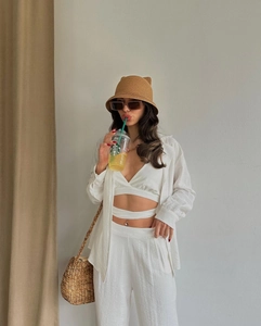Détail d'un ensemble trois pièces en lin blanc avec haut licou, chemise et pantalon
