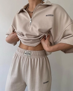 Close-up of beige semi-zipper polo sweatshirt fabric and brand logo detail on the chest