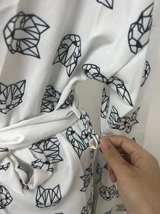 Detail der Gürtelschlaufe und Bindegürtel an weißem Schlafanzug mit Katzenprint