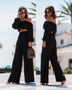 Detail of black two-piece set featuring off-shoulder crop top and high-waisted wide-leg trousers