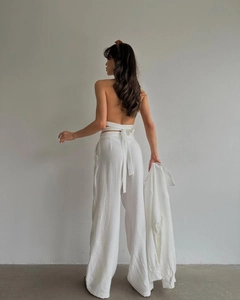 Détail d'un ensemble trois pièces blanc avec haut dos nu et pantalon large taille haute