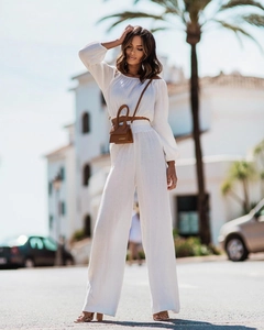 Detail of white off-shoulder top and high-waist trousers with textured cotton linen fabric