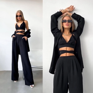 Détail d'un ensemble 3 pièces noir avec haut court à lacets et pantalon à jambes larges