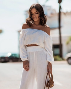 Detail of white off-shoulder crop top and high-waisted trousers in textured crepe fabric