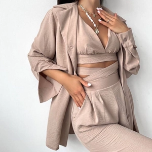 Détail d'un ensemble trois pièces beige texturé avec gilet à lacets et veste blazer