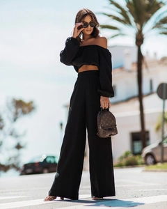 Detail of black two-piece set with off-the-shoulder crop top and wide-leg pleated trousers