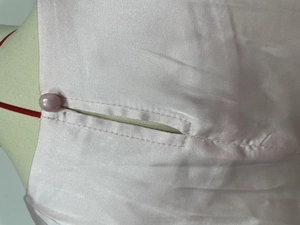 Vue macro détaillée de la fermeture à bouton perle sur l'ensemble en satin rose