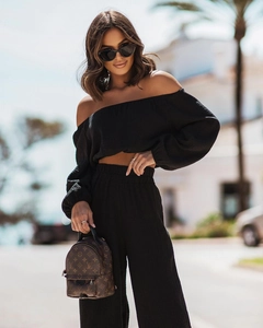 Detail of off-shoulder crop top and high-waisted wide-leg trousers in black fabric