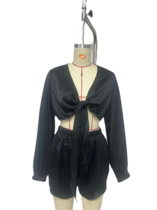 Detail view of black satin two-piece set with tie-front long sleeve top and shorts