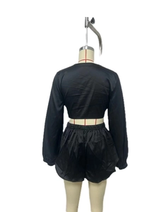 Rear view of black satin two-piece set featuring long sleeve crop top and elastic shorts