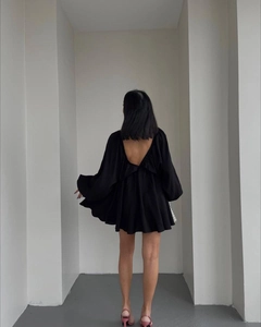 Detail des eleganten rückenfreien Designs dieses schwarzen Minikleids mit Puffärmeln