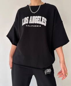 Detail of raw hem edges and white Los Angeles lettering on black street style set