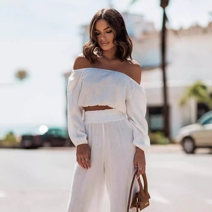 Women's white two-piece set featuring off-shoulder long sleeve crop top and wide-leg pants