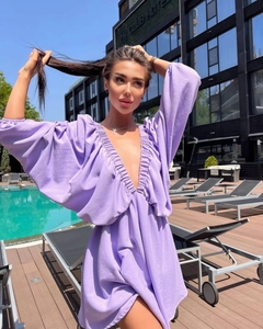 Detail of lavender deep V-neck mini dress with lantern sleeves by a sunny pool