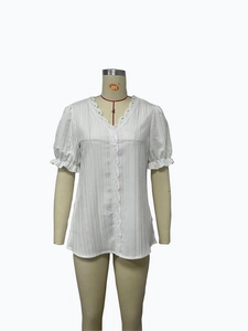 Detailed view of white V-neck blouse featuring delicate lace trim and pleated fabric
