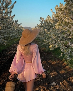 Outdoor view of woman from behind in pink satin crop top and shorts set in blooming garden