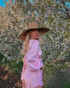 Pink satin long sleeve two-piece set styled with a straw hat under cherry blossoms