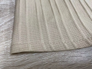 Close-up of khaki ribbed knit fabric showing detailed texture and stitched hemline