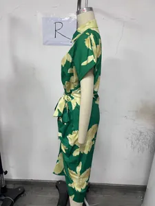 Side view of a green floral shirt dress with short sleeves and waist tie on a mannequin