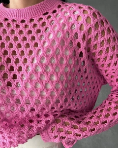 Detail of bright pink crochet knit sweater with hollow mesh texture and ribbed crewneck