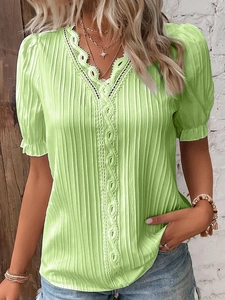 Close-up of light green V-neck top featuring delicate white lace trim and textured fabric