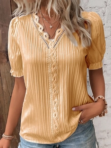 Detailed close-up of yellow pleated shirt featuring beige lace crochet trim and V-neckline