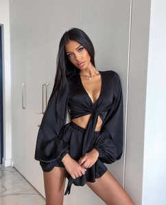 Detail of black satin two-piece set featuring cross lace-up top and matching shorts