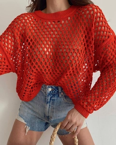 Close-up of red hollow out crochet knit sweater with intricate mesh texture detail